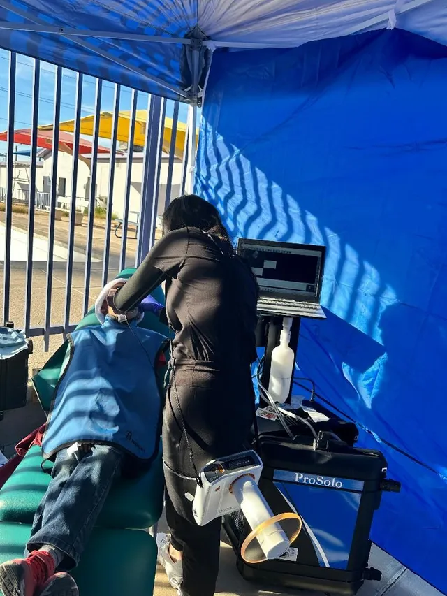 TheSmileZone team member setting up dental equipment under an outreach tent